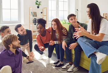 Group of diverse happy young friends men and women in casual clothes sitting on sofa at home discussing funny story and talking with each other on meeting. Friendship, party and home leisure concept.