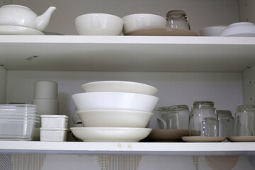 Clean dishes and tableware on a white shelf