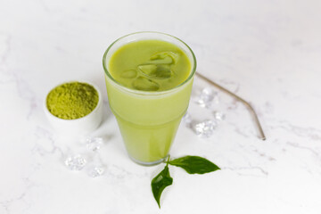 Japanese iced matcha latte, green tea with milk, soy milk with a straw in a glass against a light background. 
 