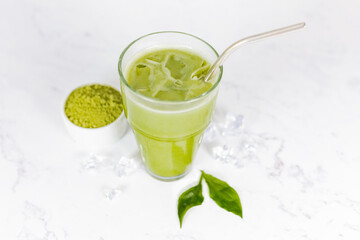 Japanese iced matcha latte, green tea with milk, soy milk with a straw in a glass against a light background. 
 