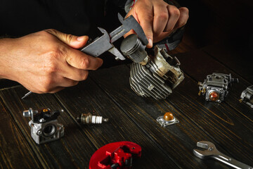 A master repairman at his desk in the workshop repairs the engine of a lawn mower after a...