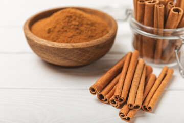Cinnamon sticks on a textured wooden background. Cinnamon roll. Spicy spice for baking, desserts and drinks. Fragrant ground cinnamon. cinnamon powder Close-up. Place for text. copy space