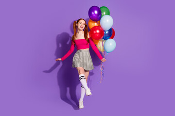 Full length photo of cheerful carefree lady dressed pink top rising balloons bouquet empty space isolated violet color background