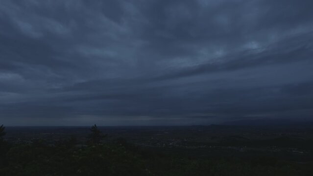 brevissimo timelapse con vista panoramica, dall'alto, del passaggio di nuvole scure nel cielo, sopra il territorio in pianura del nord est Italia, di sera, al tramonto, in un'atmosfera cupa