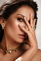 Beautiful tanned woman with smoky makeup, gold jewelry and ice. Beauty face.