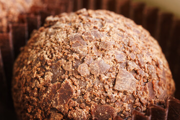 Delicious handmade chocolate candy, sprinkled with crispy shavings, in a paper tartlet. Photo. Macro. Selective focus