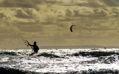 Kite surfer riding waves. Kiteboarding sport.