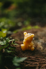 Handmade candles from natural beeswax in the shape of flowers, bears on an old stump in the forest. Hobby. Handmade present. Gift. Artistic photo of beekeeping products against the backdrop of nature