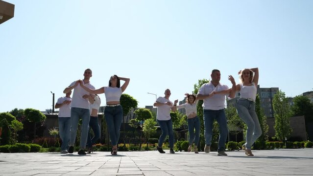 City Festival people enjoy dancing on street, crowd reiterate movements after dance trainer outdoors. Bachata street dance