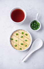 Asian steamed eggs in a bowl with soy sauce and scallions