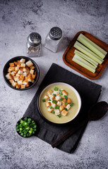 Celery greens soup with scallions and croutons in a bowl