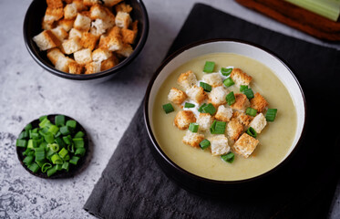 Celery greens soup with scallions and croutons in a bowl