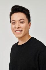 A fashionable young man with a black shirt strikes a pose with a cheerful smile on his face.