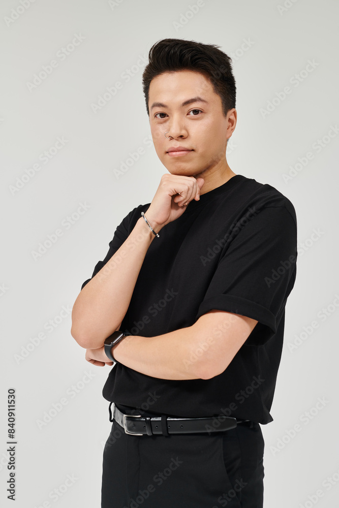 Wall mural a fashionable young man in elegant attire strikes a confident pose for a camera in a black shirt.