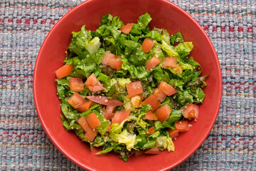 Bol con ensalada de lechuga y trozos de tomate