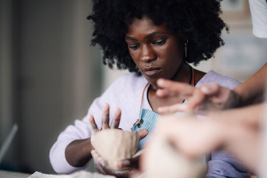 Portrait of diverse pottery class attendee shaping clay mug at studio. - Powered by Adobe