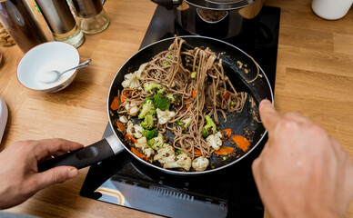 Chef at the kitchen preparing japanese buckwheat pasta with lentils