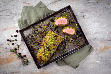 Gebratenes Mangalica Schweinefilet ummantelt mit zerkleinerten Pistazien, geriebenem Parmesan und gehackten Preiselbeeren serviert mit Prinzesskartoffeln 