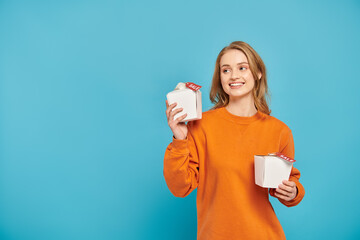 A girl happily holds two boxes of Asian food in her hands with sales tag.