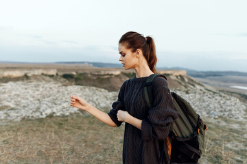 adventurous woman standing on hilltop with backpack, enjoying scenic landscape view