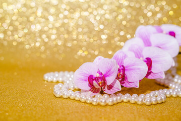 A branch of white orchids on a shiny gold background
