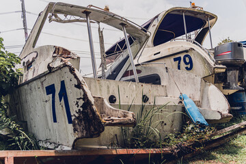 Old and rusty motor boats on a landfill surrounded by tropical forest