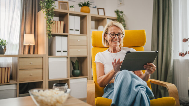 Mature senior woman sit at home and use tablet