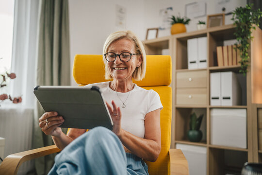 Mature senior woman sit at home and use tablet
