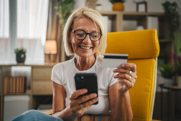 Mature senior woman buy online with credit card and on mobile phone at home