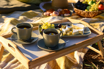 Picnic with tasty food and tea in field at sunset, closeup