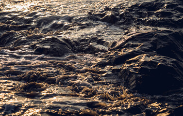 A large rocks surrounded by waves of the ocean