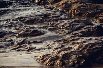 A large rocks surrounded by waves of the ocean