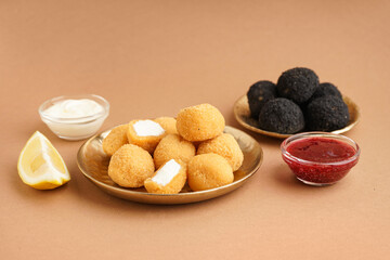 Plates with different delicious fried mozzarella balls and sauces on beige background