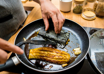Chef at the kitchen preparing grilled eggplants with garlic