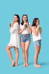 Fototapeta premium Beautiful young women with glasses of cocktail on blue background. Summer party