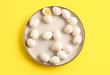 Plate with fresh boiled quail eggs on yellow background