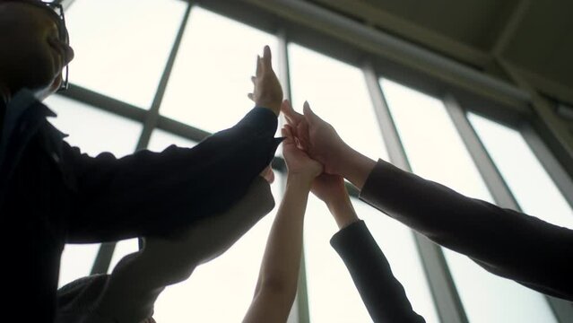 Close-up of hands giving five of asian business group together to cheer up for team building with diverse partnership, group of successful entrepreneurs engage collaboration with startup team.
