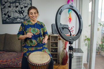 Fototapeta premium Happy Woman doing a live on the phone at home playing her drum