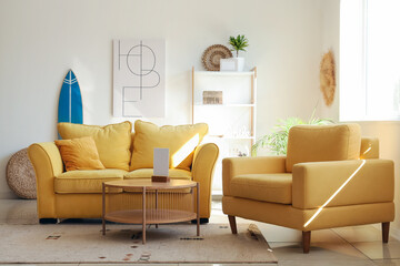 Comfortable sofa, cozy armchair and surfboard in interior of living room