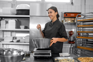 Woman in uniform kneading dough in kitchen preparing pastry in kitchen