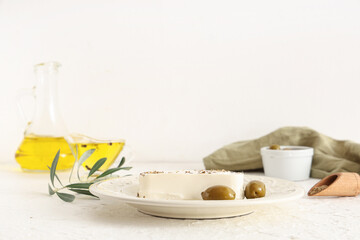 Plate with tasty feta cheese, spices and olives on white background