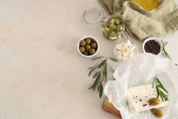 Paper with tasty feta cheese, olives, rosemary and peppercorn on white background