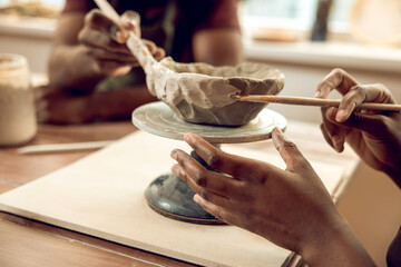 Close up of a human hand with a brush and a clay mug