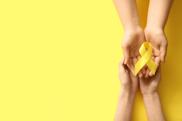 Fototapeta premium Women holding yellow ribbon on color background. Sarcoma concept.