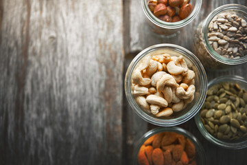Bowls, cashew and nuts on table, above and mock up space for nutrition, health and promotion for wellness. Almond, hazelnut and pumpkin seeds in glass container for meal prep with food at apartment