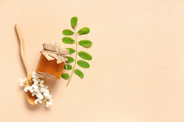 Jar of sweet honey with acacia flowers and wooden spoon on beige background