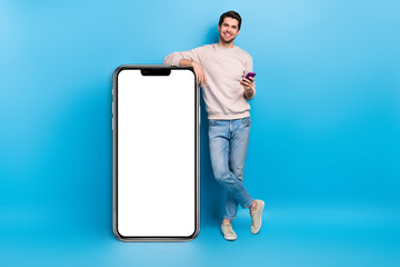 Full size photo of nice young man use smart phone empty space placard wear beige sweatshirt...