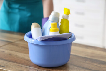 Female janitor with cleaning supplies on table in kitchen, closeup