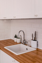 Clean white sink on wooden table in white kitchen