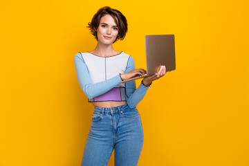 Portrait of pretty girl hold use wireless laptop communicate social network isolated on yellow...
